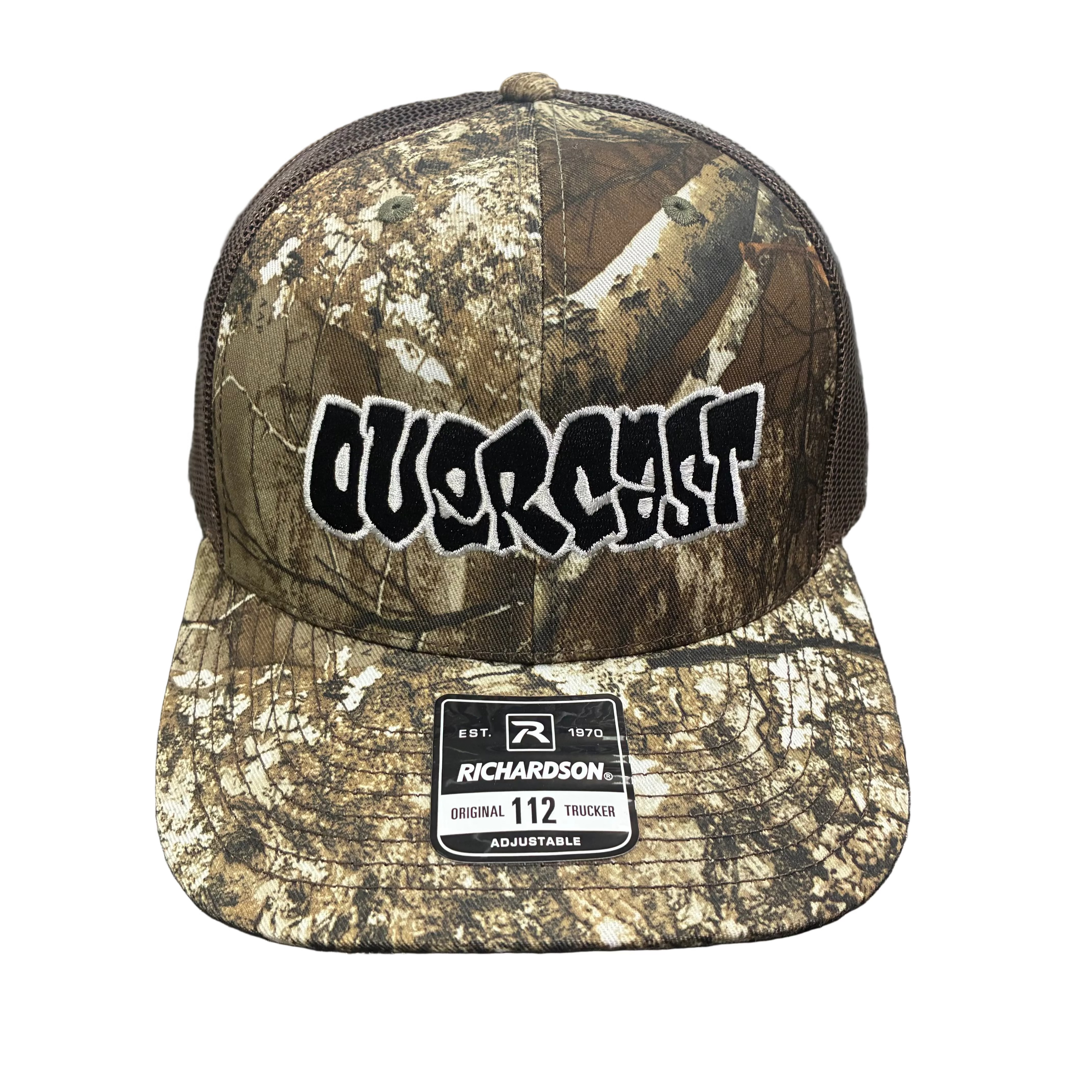Camouflage cap with 'Overshirt' branding on a textured surface